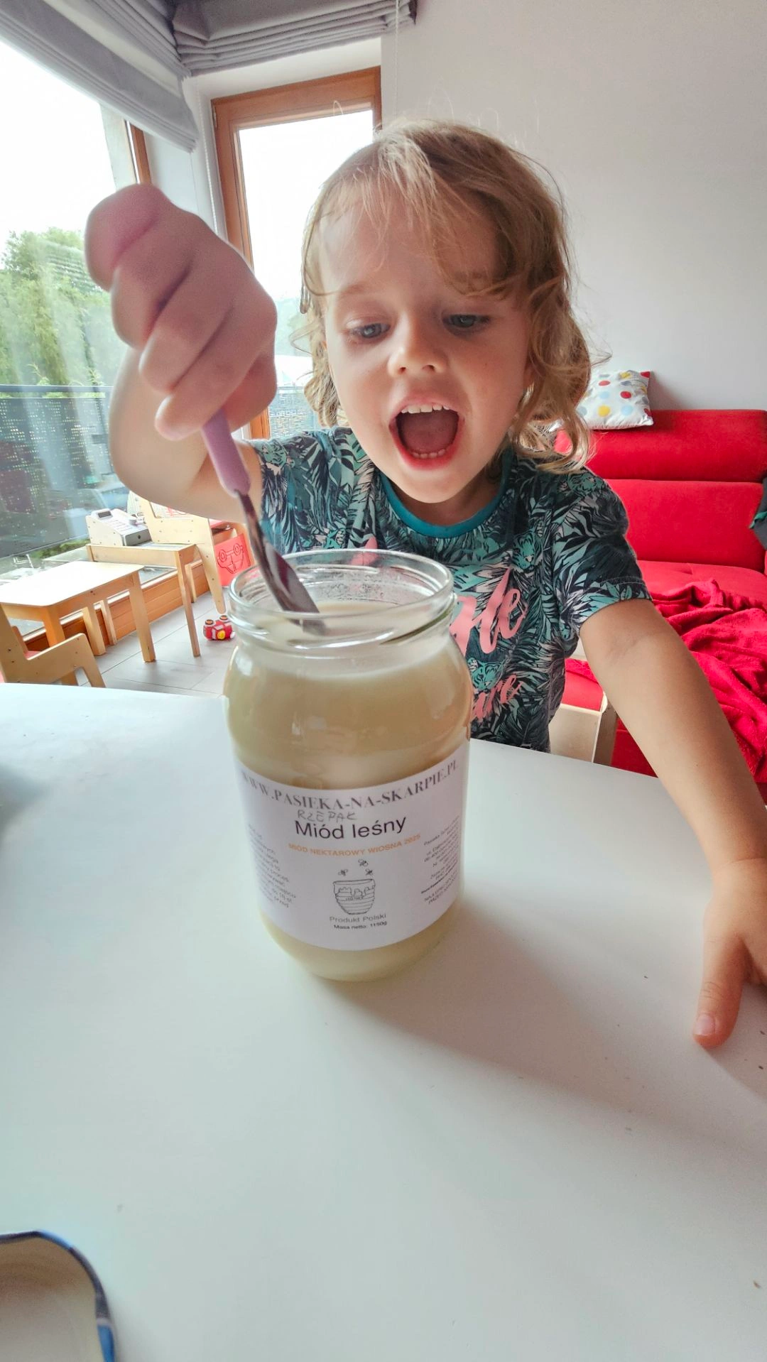 Uśmiechnięte dziecko jedzące naturalny miód z Pasieki Na Skarpie.